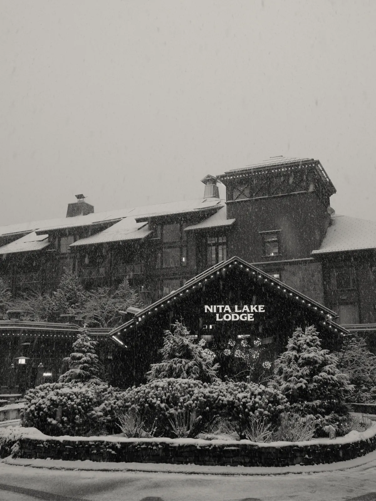 The exterior of Nita Lake Lodge in the snow at night.